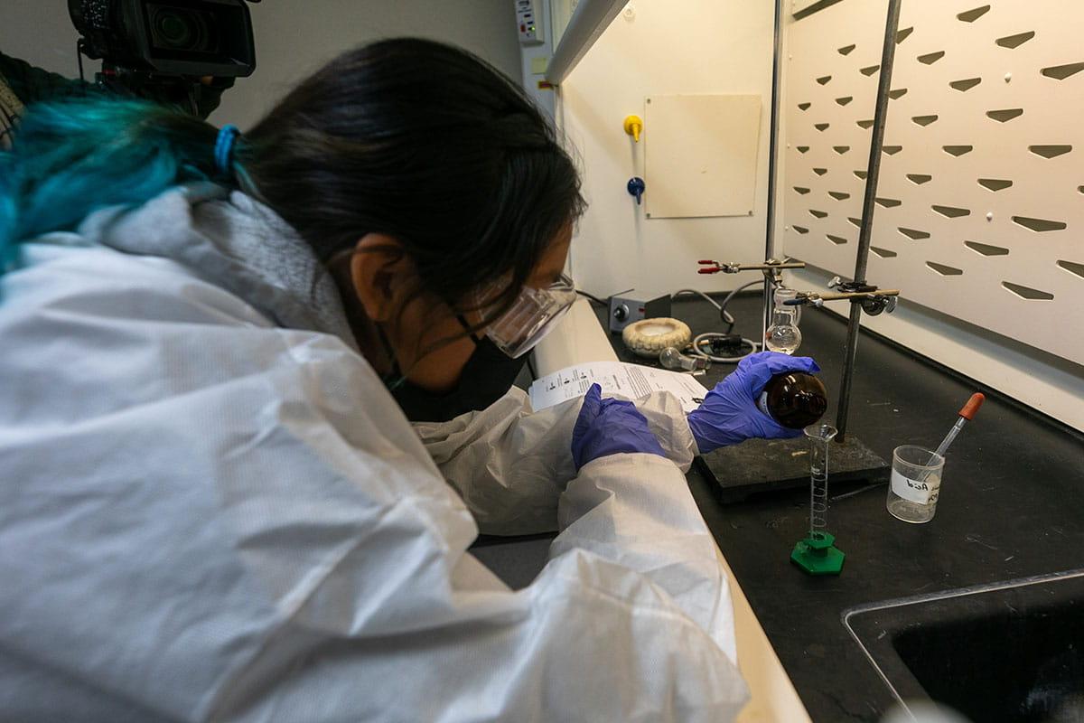 A 太阳集团娱乐场登陆网站 student pouring a liquid into a test tube in a chemistry lab