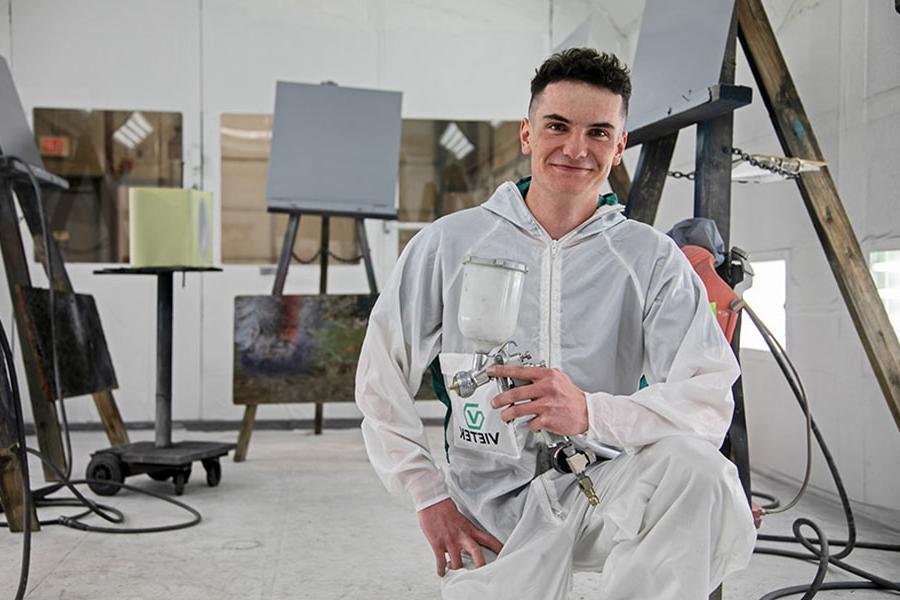 太阳集团娱乐场登陆网站 student holding a paint sprayer in the 汽车的身体 paint booth